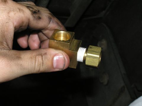 2000 Ford Excursion - Close-up of a brass fitting with white thread sealant, held by a hand.