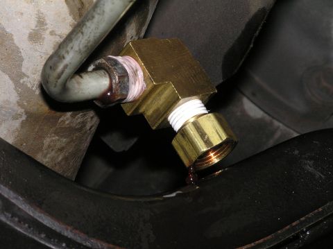2000 Ford Excursion - A brass T-fitting is installed on a vehicle's transmission fluid line, showing a small leak.