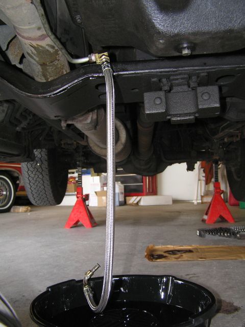 2000 Ford Excursion - Transmission fluid is being drained from the vehicle into a catch pan.