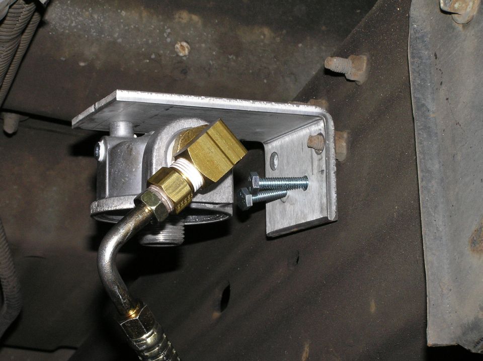 Aluminum bracket with brass fittings and metal fuel line mounted to vehicle frame rail