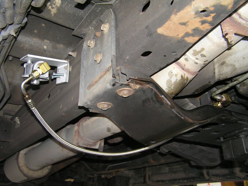 Undercarriage view with braided steel hose and brass fittings mounted to aluminum bracket on black frame