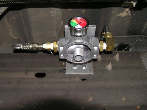2000 Ford Excursion - A close-up view of a transmission filter housing with a gauge, installed on the undercarriage of a vehicle.