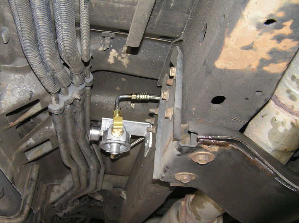 Undercarriage-mounted brass/aluminum valve on bracket with steel and braided fuel lines along frame rail