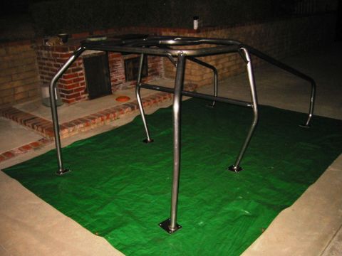 1985 Ford Bronco - Roll cage assembly on a green tarp, with a brick structure in the background.
