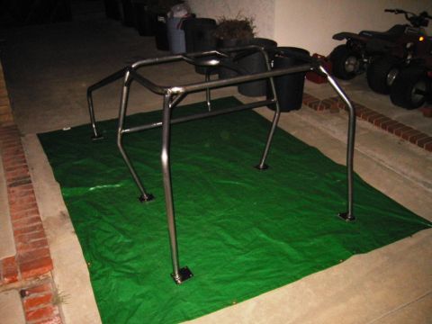 1985 Ford Bronco - A chrome roll cage is set up on a green tarp, with ATVs visible in the background.