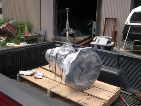 1989 Ford Bronco - Transmission wrapped in plastic sits on a wooden pallet in the bed of a pickup truck.