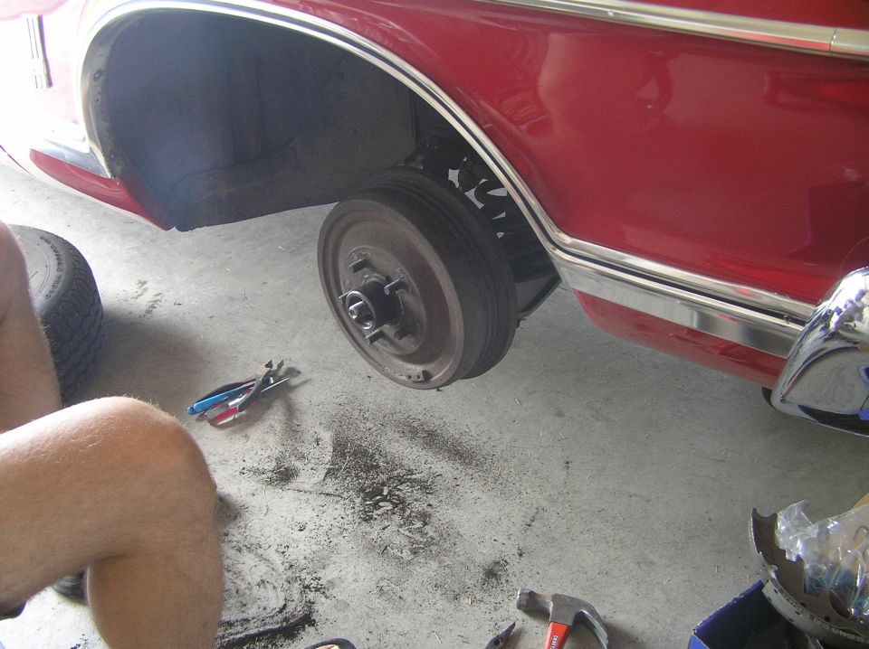 Exposed brake drum and hub on red Galaxie with wheel removed in garage