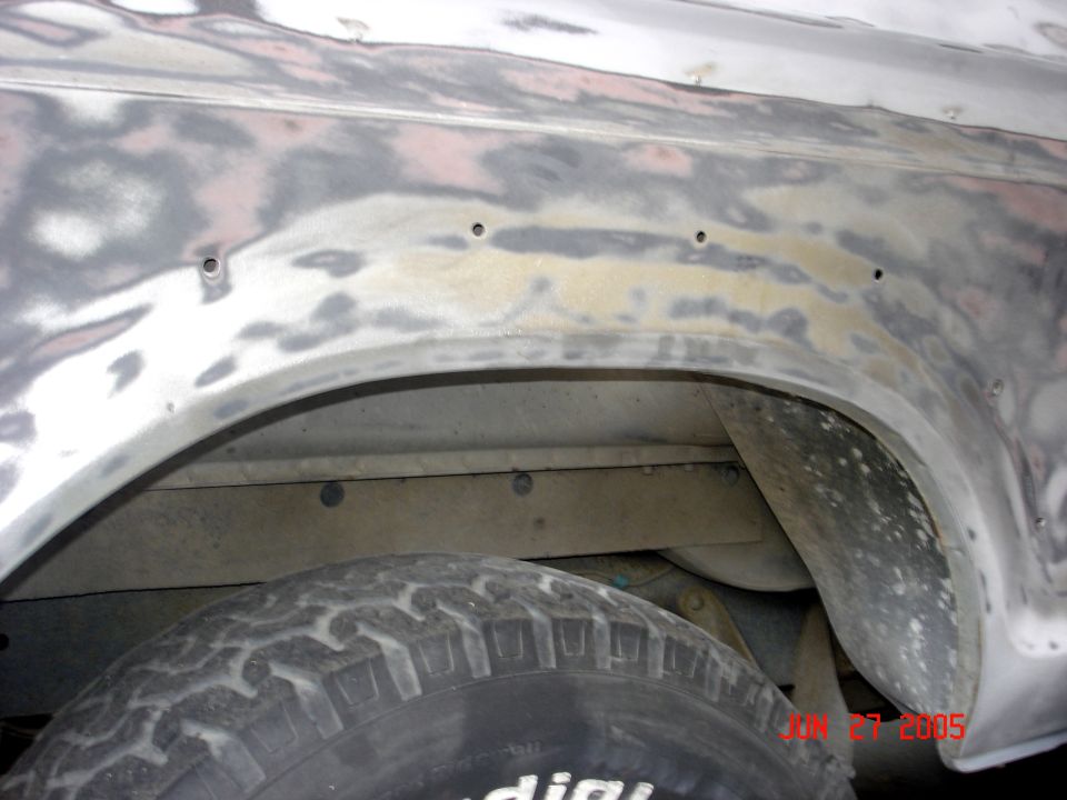 Sanded bare-metal rear fender and wheel arch with mud tire below, dated June 27 2005.