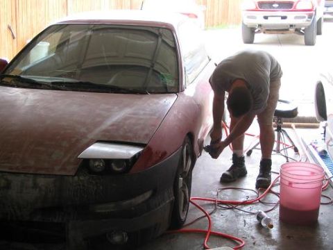 1994 Ford Probe - A person sands a red 1994 Ford Probe in a garage, with another truck visible in the background.