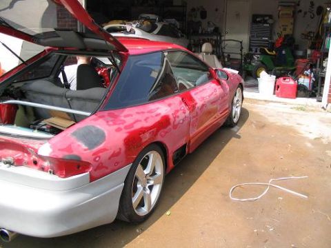 1994 Ford Probe - A red 1994 Ford Probe is shown in a garage with its rear hatch open, revealing interior work and body repair in progress.