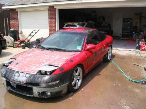 1994 Ford Probe - A red 1994 Ford Probe sits in a driveway, appearing to be in the middle of bodywork or repairs.