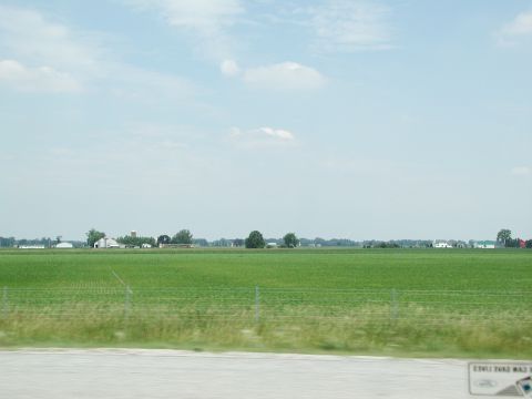 1992 Ford Taurus - A wide view of farmland with buildings in the distance and a fence in the foreground.