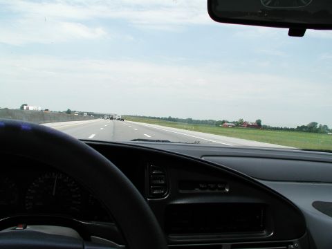 1992 Ford Taurus - View from inside a car driving on a highway with other vehicles and farmland in the distance.