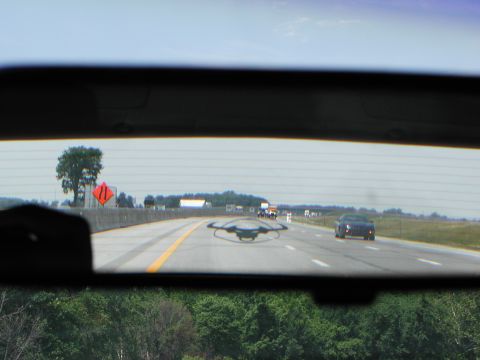 1992 Ford Taurus - View of a black sedan on the highway, seen through the rear window of another vehicle.