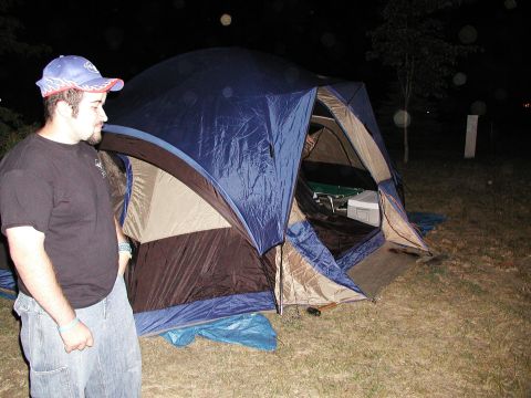 1992 Ford Taurus - A man stands next to a large blue and tan tent at night, with camping gear visible inside.