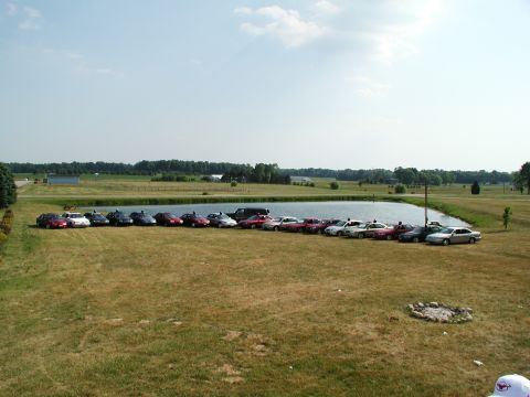 1992 Ford Taurus - A collection of 1992 Ford Tauruses are parked in a line next to a body of water on a sunny day.
