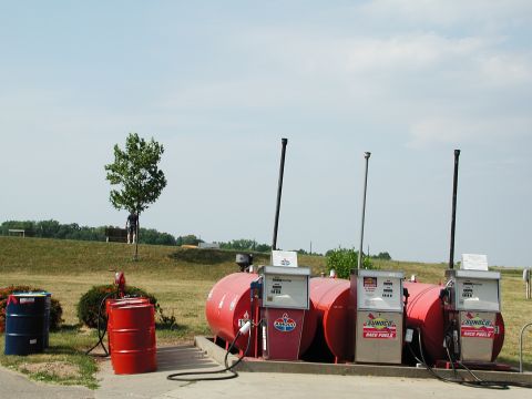 1992 Ford Taurus - A rural gas station scene with multiple pumps and storage tanks under a clear sky.