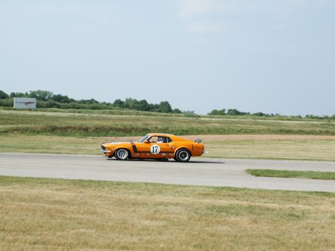 1992 Ford Taurus - A vintage orange Ford Mustang race car with number 17 speeds down the track under a clear sky.