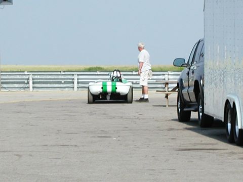 1992 Ford Taurus - A man stands next to a small race car on a track, with an SUV and trailer in the background.
