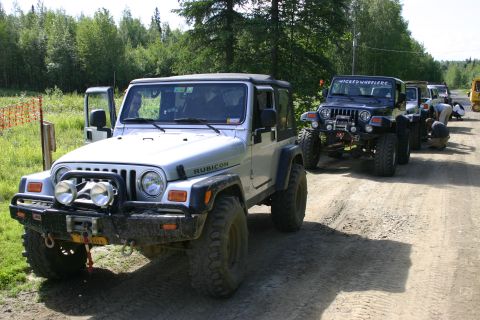 2003 Jeep TJ - Several Jeeps lined up on a dirt road, with people attending to them.