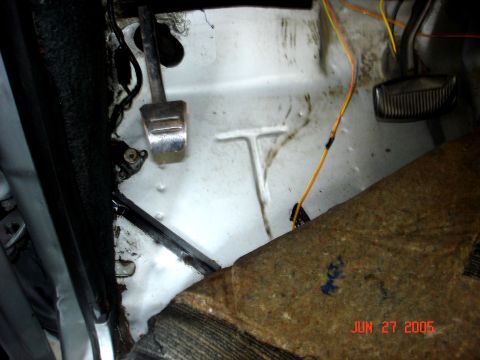 1979 Ford Bronco - The floor pan of a vehicle shows pedals, wiring, and some carpeted material.