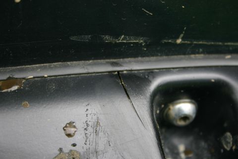 2003 Jeep TJ - Close-up of a damaged dark green painted panel with a visible crack and a bolt.