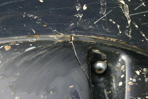 2003 Jeep TJ - A close-up view shows a cracked black plastic component, likely from a vehicle's interior or exterior trim, with a visible bolt securing it.