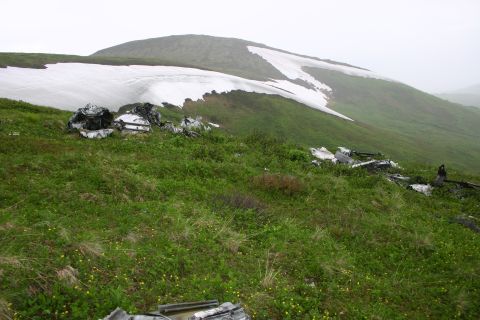 2003 Jeep TJ - Debris is scattered across a grassy mountainside with patches of snow, suggesting a past incident.