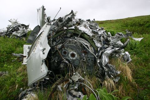 2003 Jeep TJ - Debris from a crashed aircraft lies scattered in a grassy field.