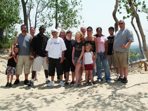 1992 Ford Taurus - A group of people gathered on a sandy dune, with trees and a scenic overlook in the background.