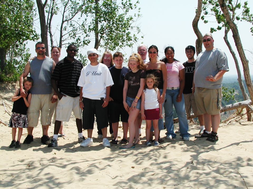 Group of people posing on a sandy dune with trees and a distant view