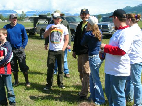 2003 Jeep TJ - People gathered in a field with vehicles and mountains visible.
