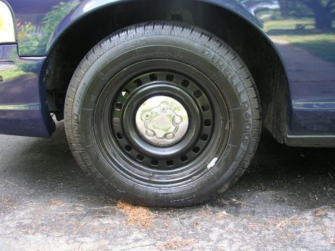 1999 Ford Crown Victoria - A close-up view of a car's wheel and fender, showing the tire and hubcap.