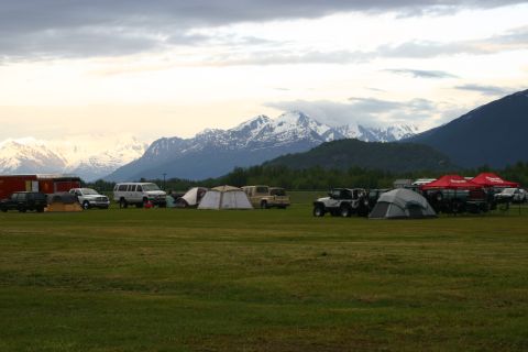 2003 Jeep TJ - A group of Jeeps and tents are set up in a grassy field with a mountain range behind them.