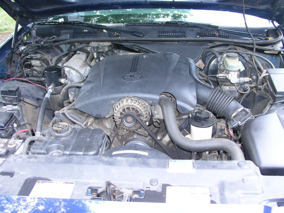 1999 Ford Crown Victoria engine bay with black engine cover and visible alternator