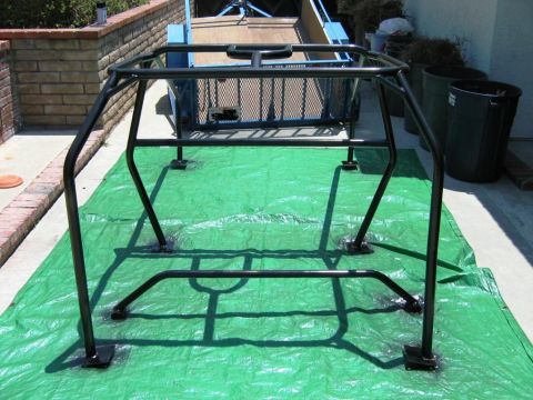 1985 Ford Bronco - Roll cage assembly on a green tarp, with a trailer visible behind it.