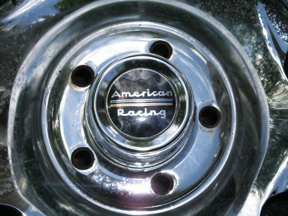 Chrome wheel with a center cap that says American Racing