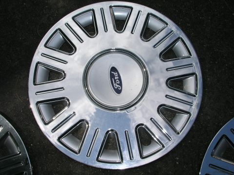1999 Ford Crown Victoria - A single chrome Ford wheel cover is shown, reflecting the sky and surroundings.