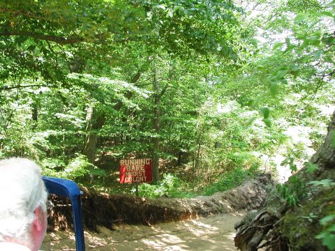 1992 Ford Taurus - A dirt path winds through a wooded area, marked by a sign indicating 'RUNNING BARE NUDIST COLONY'.