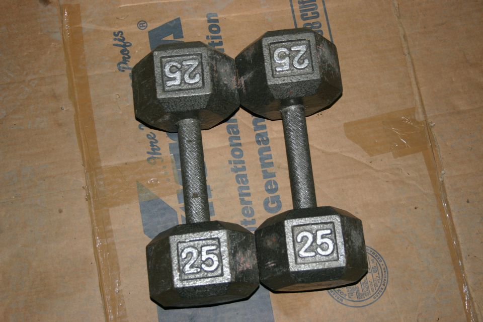 Two hex-shaped 25lb dumbbells on a cardboard surface with text