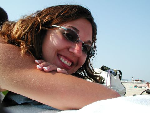 1992 Ford Taurus - A woman enjoys a sunny day at the beach, with a bag and the ocean visible.