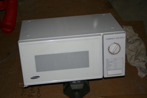 2003 Jeep TJ - A Samsung microwave is shown, supported by a weight, with a red hose and a rag in the background.