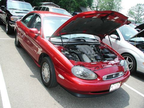 1992 Ford Taurus - A red sedan is parked with its hood open, revealing the engine compartment.