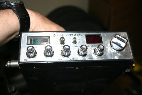 2003 Jeep TJ - Close-up of a Cobra 140 GTL CB radio, held by a person's hand.