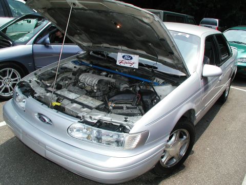 1992 Ford Taurus - Engine bay of a 1992 Ford Taurus, a Ford Racing sign and a strut bar.