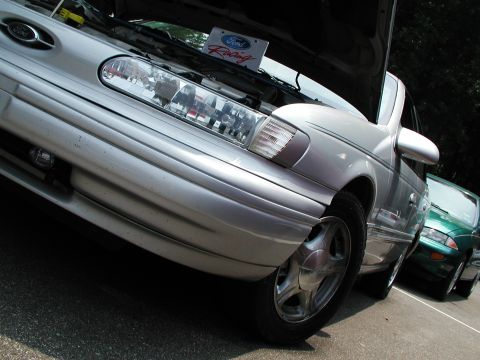 1992 Ford Taurus - A silver sedan is parked next to a green car, with its hood open, revealing a Ford Racing plate.