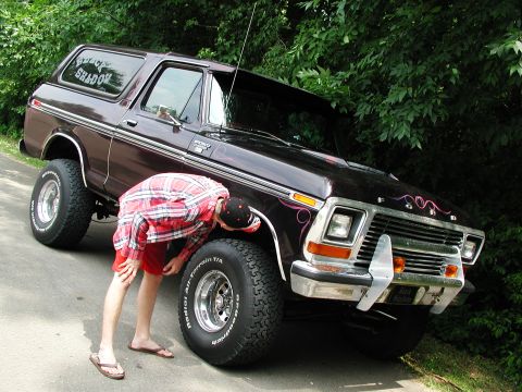 1992 Ford Taurus - Person inspects the front tire of a dark brown 1978 Ford Bronco with custom graphics.