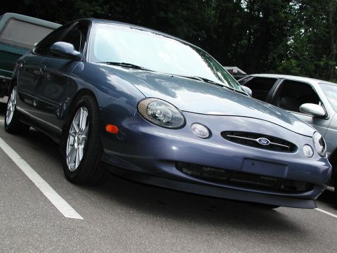 1992 Ford Taurus - A blue Ford Taurus is parked in a lot, showing its front end and side profile.