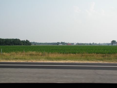 1992 Ford Taurus - Rural landscape with agricultural fields and distant farm buildings under a hazy sky.