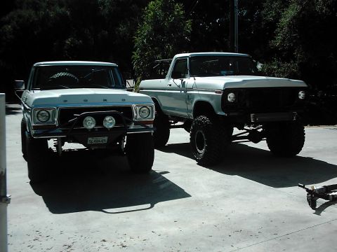 1978 Ford Bronco - Two modified Ford trucks, likely from the late 1970s, are parked outdoors on a paved surface.